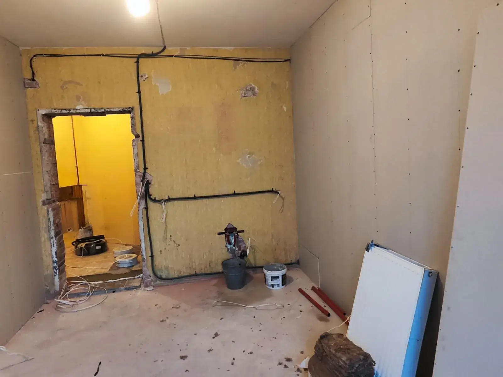 Pomieszczenie socjalne w trakcie remontu: ściany z instalacją i przejście do toalety