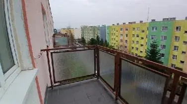 Pusty balkon przed home stagingiem z widokiem na kolorowe bloki