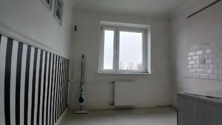 Kuchnia przed home stagingiem: puste pomieszczenie z tapetą w czarno-białe pasy