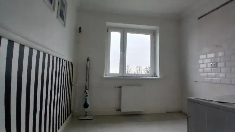 Kuchnia przed home stagingiem: puste pomieszczenie z tapetą w czarno-białe pasy