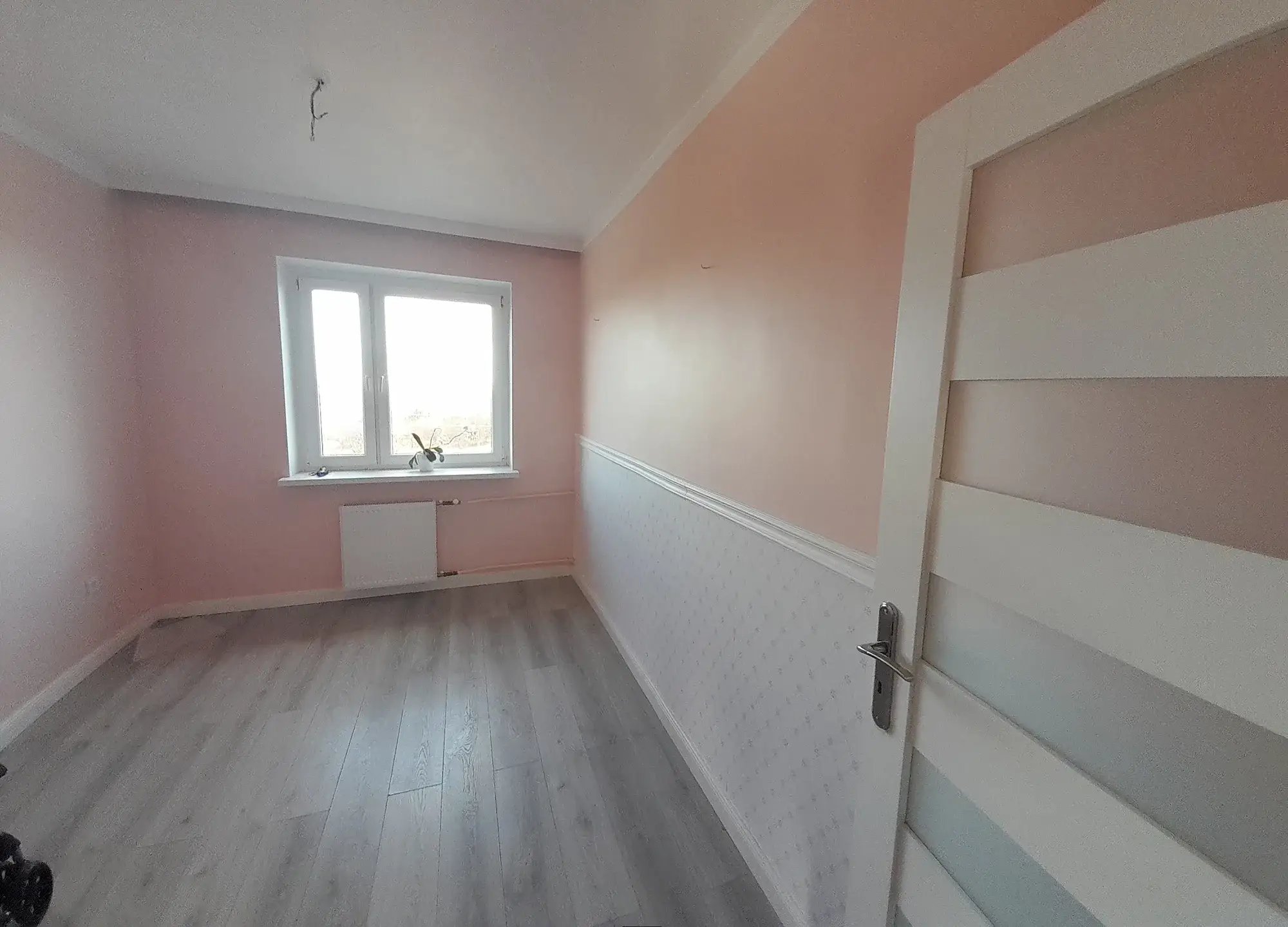 Pusty różowy pokój z lamperią przed home stagingiem