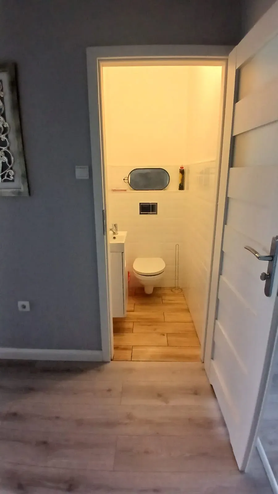 WC przed home stagingiem, widok z przedpokoju przez otwarte drzwi