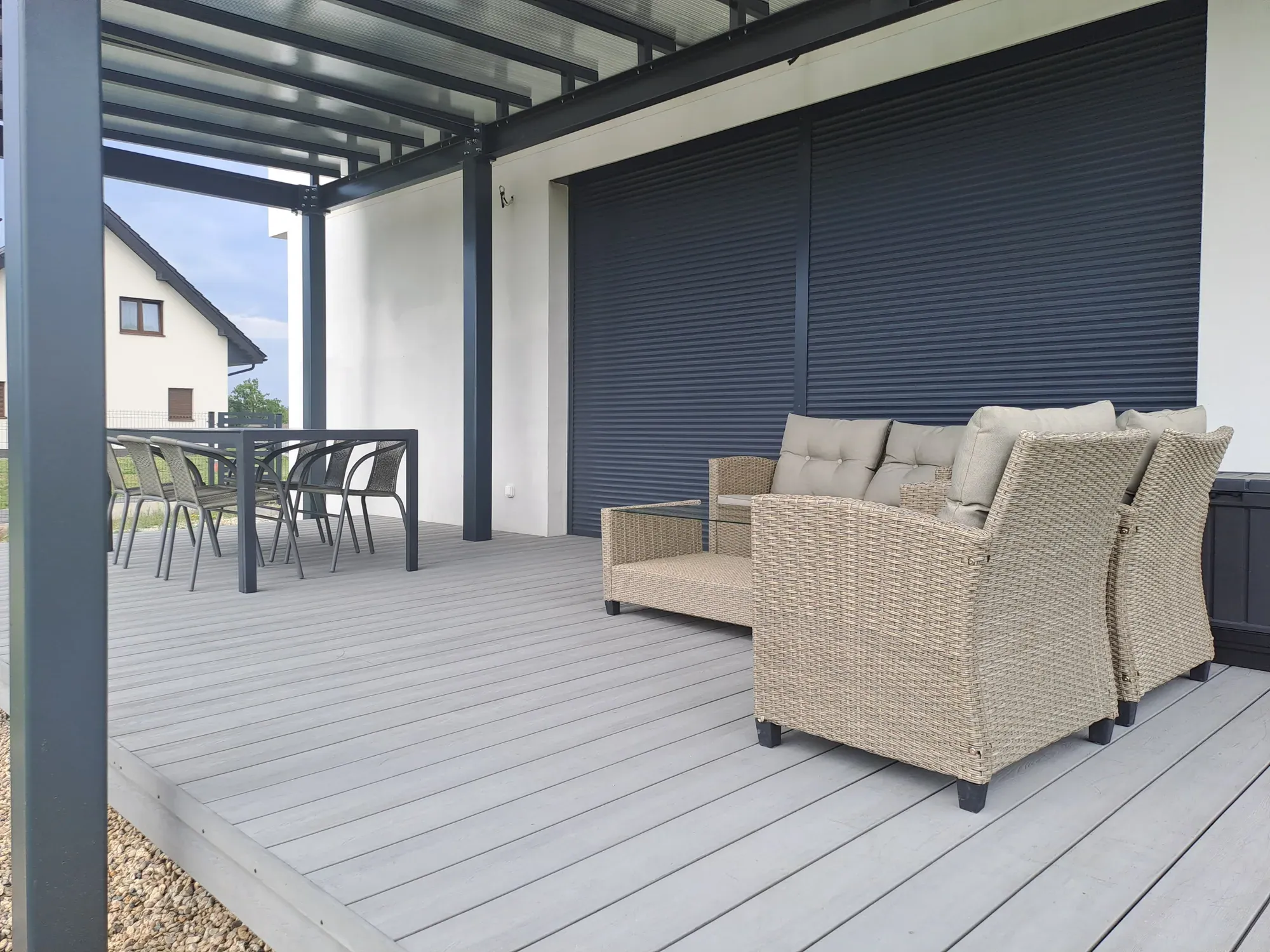Taras przed home stagingiem: wiklinowe fotele i sofa ustawione pod ścianą domu